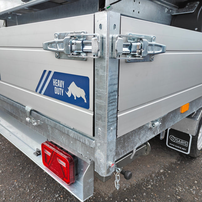 Bord sluiting SPP ZB-09A gemonteerd op lichtgrijze aluminium borden van een aanhangwagen merk Saris met afneembare hoekrongen en blauwe zelfklever "heavy duty". Op de zwarte spatlappen staat het opschrift "Saris" en de domeinnaam "www.saris.net". In de lichtbalk zijn lichten van Aspöck gemonteerd.
