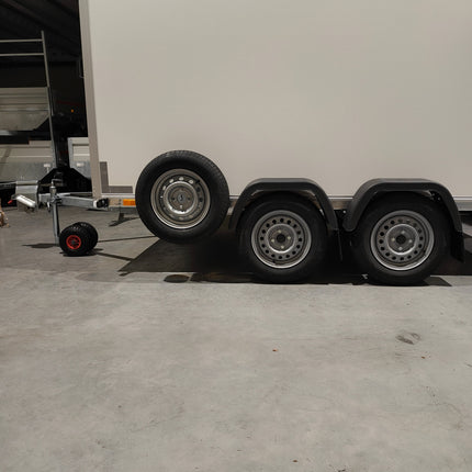 Gesloten dubbelas merk VDM Trailer afmeting 300x150cm dubbelas uitvoering met gemonteerd reservewiel op een reservewielsteun (houder) en op de dissel een gemonteerd neuswiel met dubbele off-road banden.